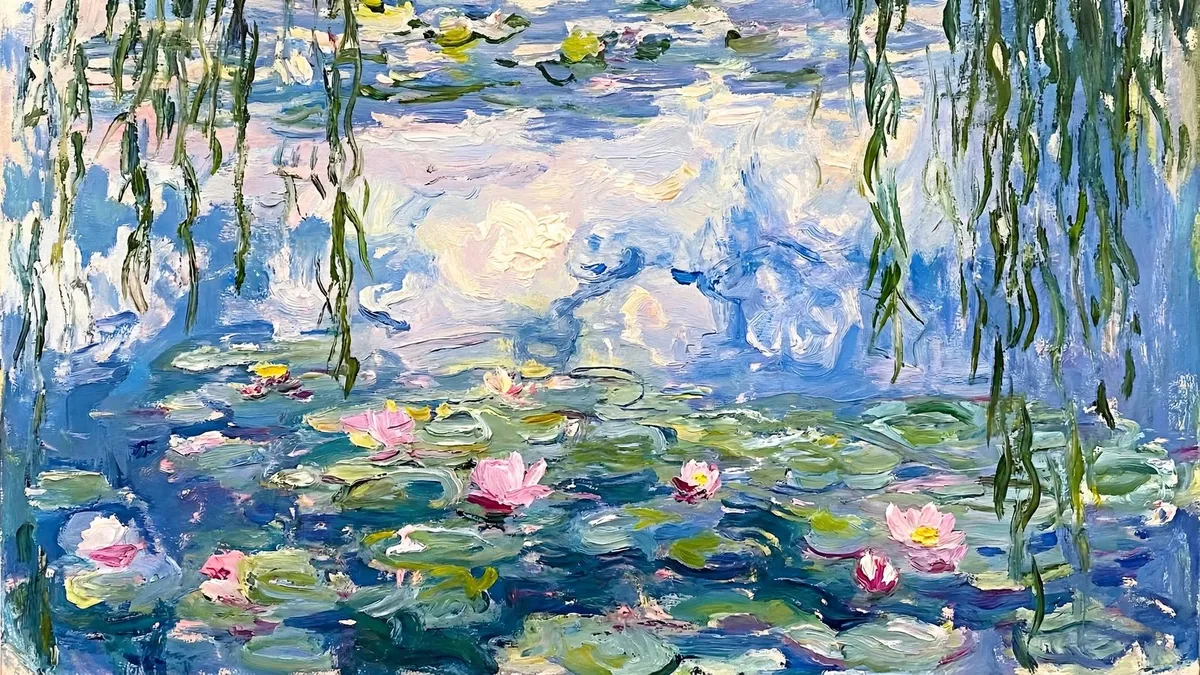 Pink water lilies and green pads on a blue pond, with willow branches hanging at the edges