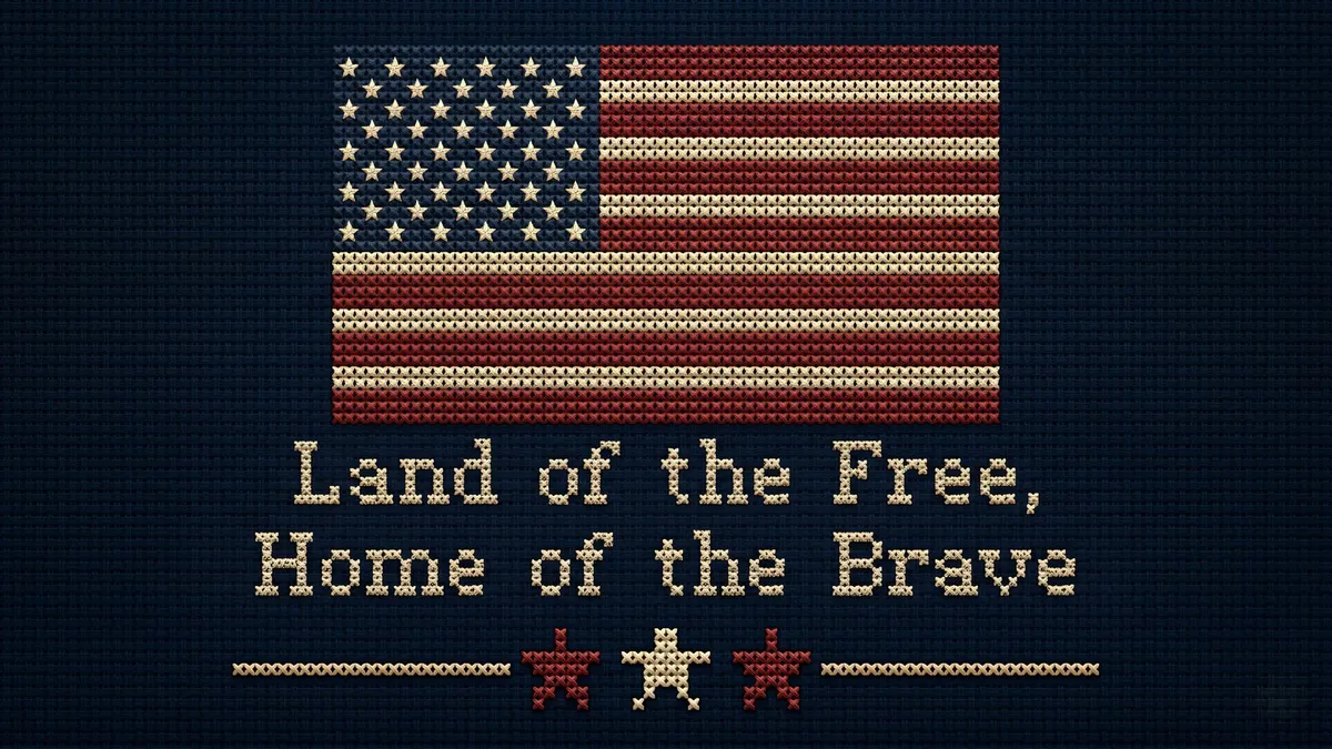 Cross-stitched American flag on navy cloth above the words Land of the Free, Home of the Brave and three stars